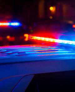 Red and blue police lights near a car crash in a city at night.