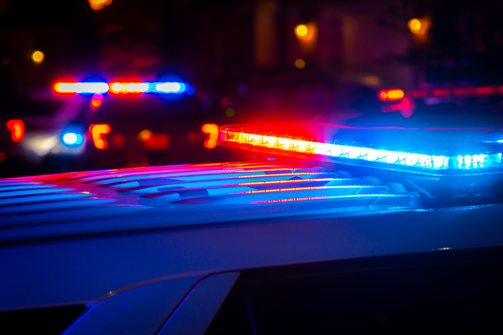 Red and blue police lights near a car crash in a city at night.